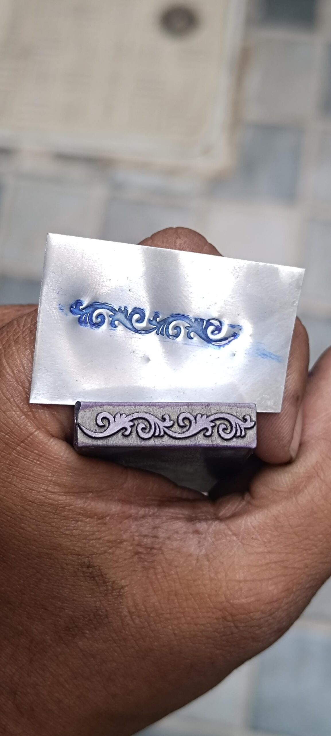 il_fullxfull.6837515110_mpsf.jpg Ornamental scroll metal stamp held beside its sample impression on metal sheet